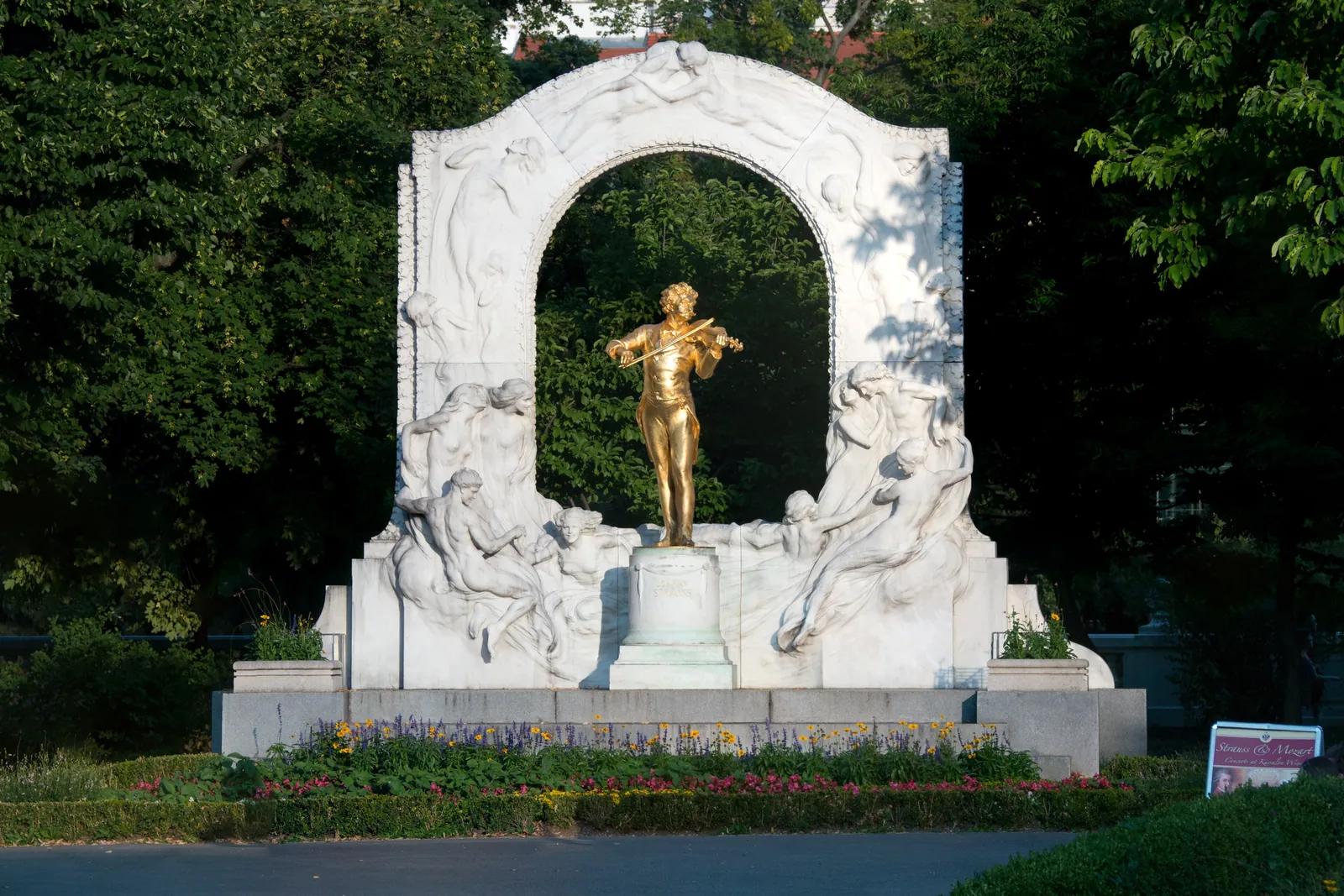 The gilded statue of Johann Strauss II playing the violin, in front of a marble arch in the Stadtpark in Vienna